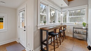 Eine moderne Küche mit Holzbalkendecke, großen Fenstern und einer Bar mit Hockern.