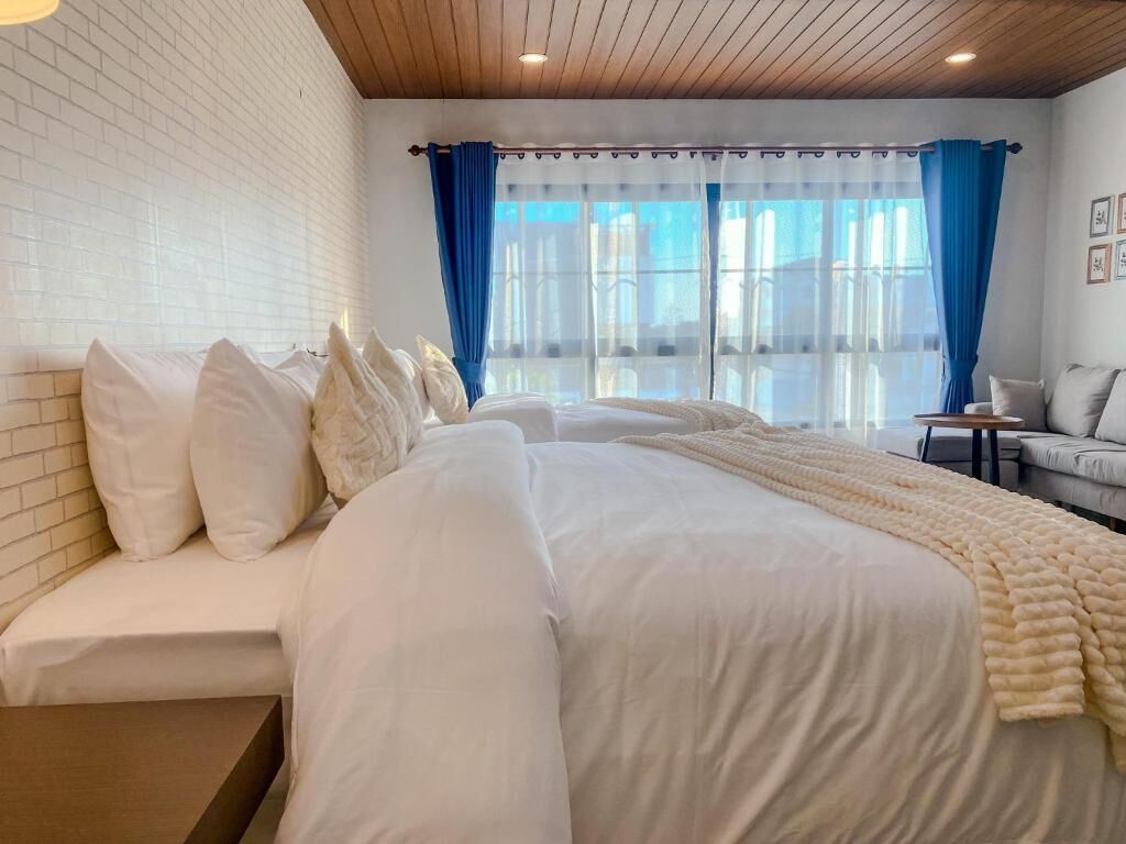 Un dormitorio con una cama grande, un sofá y una ventana con cortinas.