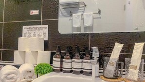 Un baño con un espejo grande, un lavabo y artículos de aseo, incluyendo jabón de manos y champú.