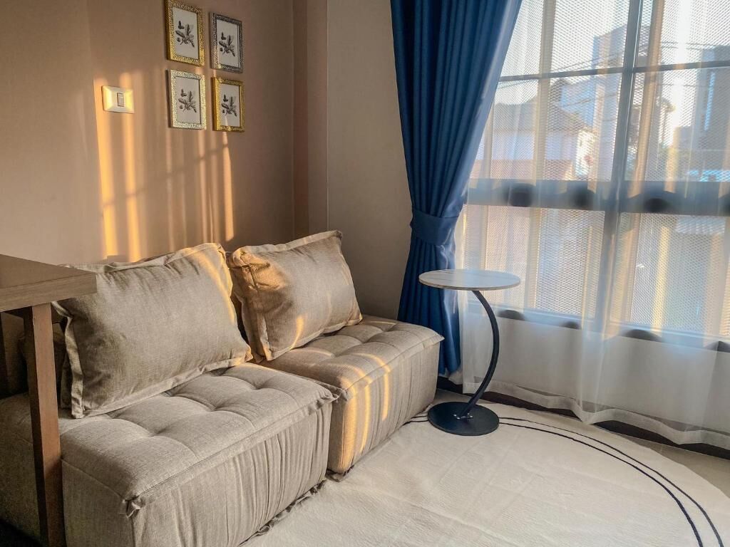 Ein gemütliches Zimmer mit einer Couch, einem kleinen runden Tisch und einem Fenster mit blauen Vorhängen.