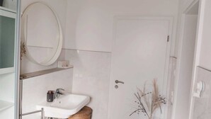 A bathroom with a white sink, a round mirror, and a door. - Studio room near Koblenz (Sankt Sebastian)