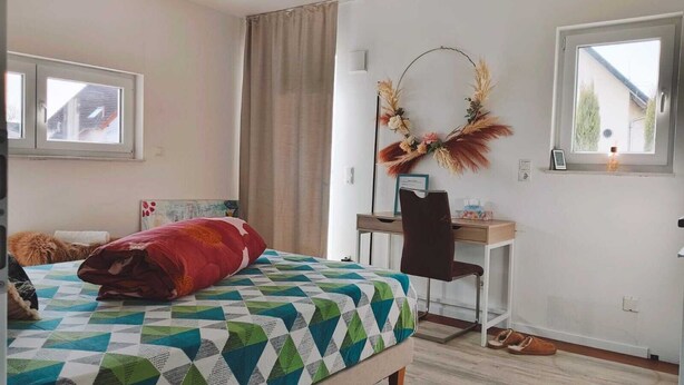 A bedroom with a bed, a desk, and a chair. There is a window on the left and another on the right. - Studio room near Koblenz (Sankt Sebastian)