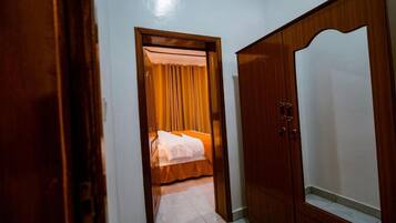 Un pasillo estrecho que conduce a un dormitorio con cama y armario.