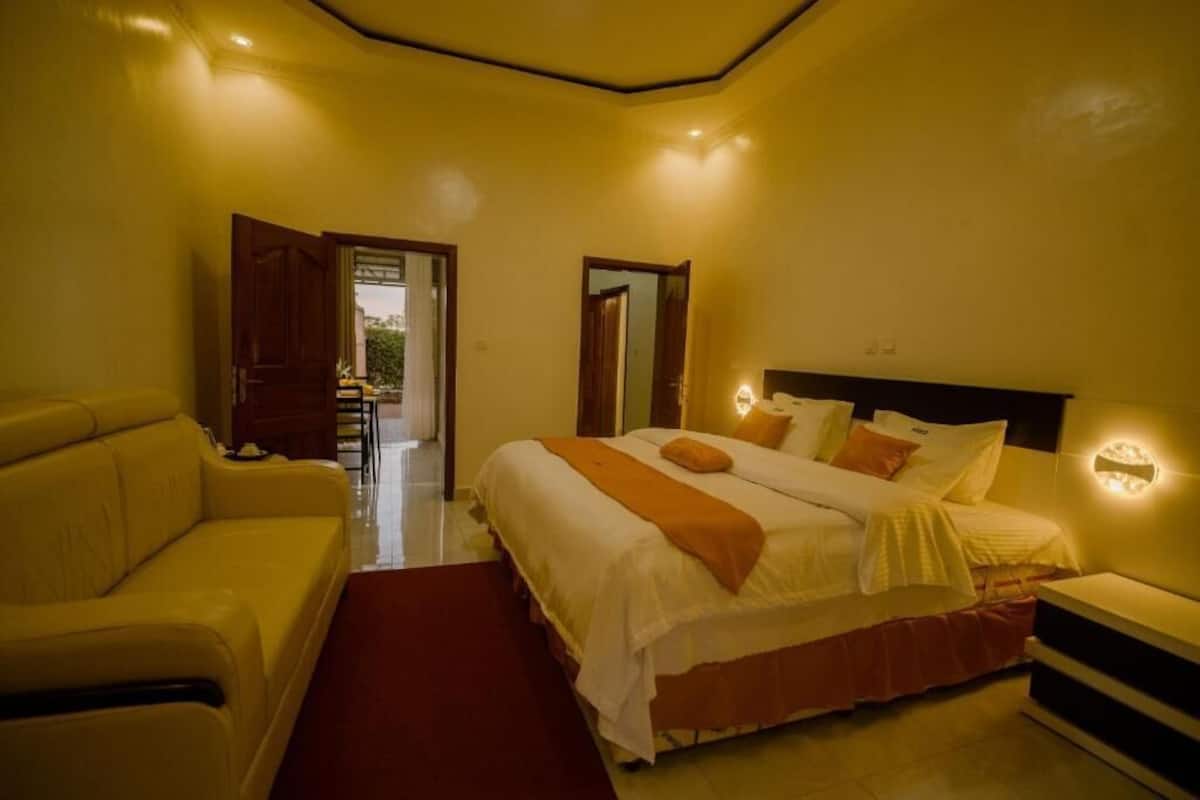 A hotel room with a bed, a sofa, and a nightstand.