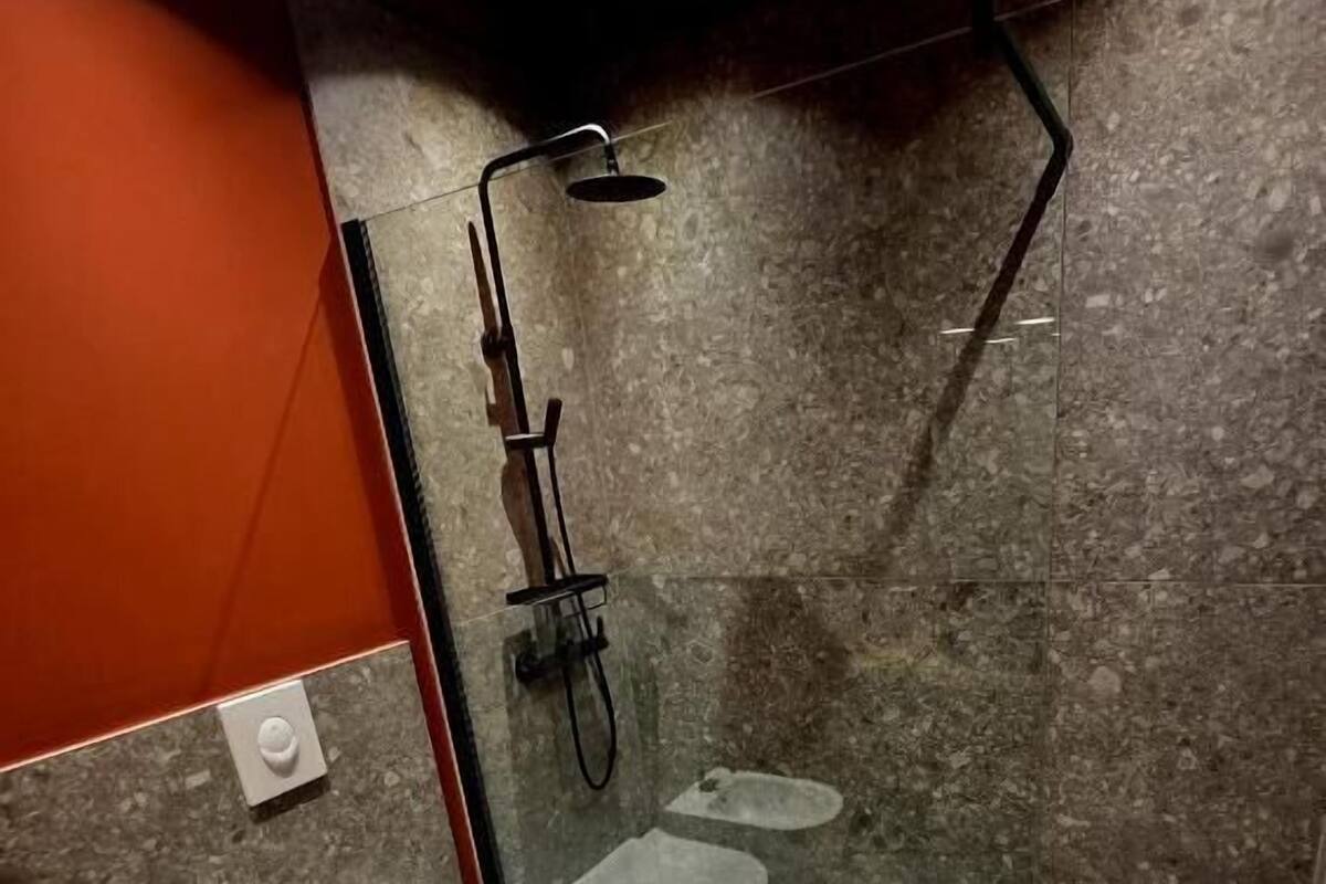 A modern bathroom with a glass shower enclosure, a white toilet, and a sink.