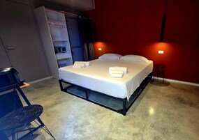 Un dormitorio moderno con cama, mesitas de noche, un armario y una pequeña mesa redonda.