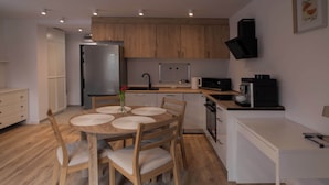 Una cocina compacta con armarios de madera, un refrigerador, un microondas y una cafetera.
