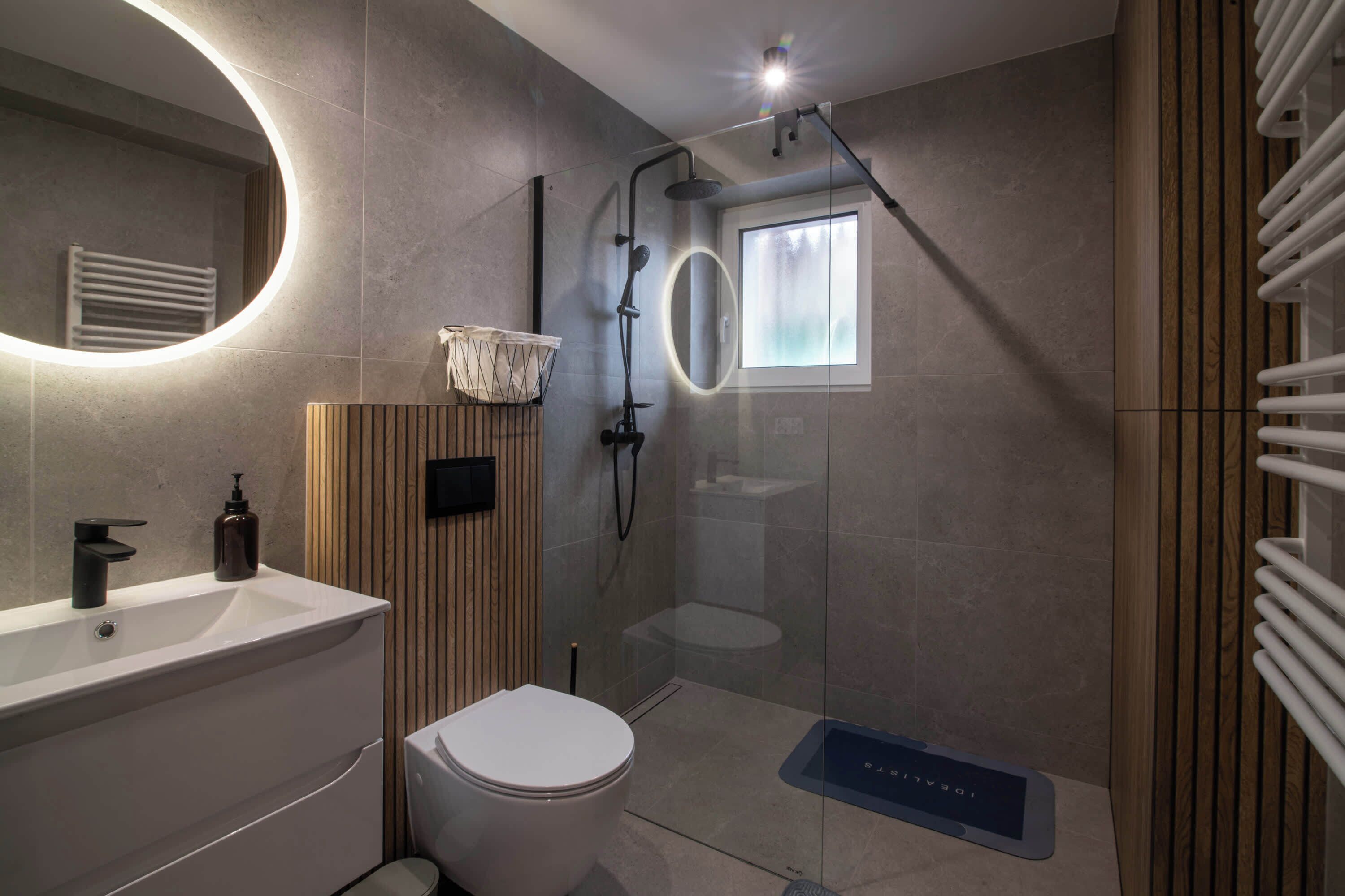 A modern bathroom with a shower, toilet, and sink.