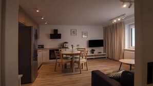 Una cocina moderna con armarios de madera, un refrigerador empotrado y una zona de comedor con una mesa redonda y sillas.