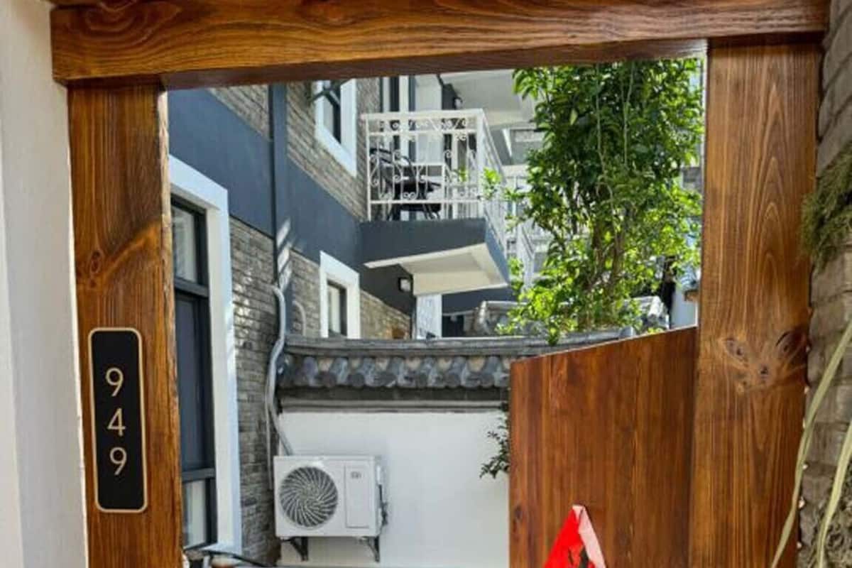 Une porte en bois avec une plaque portant un numéro, une petite table et un appareil de climatisation visible à travers la porte.