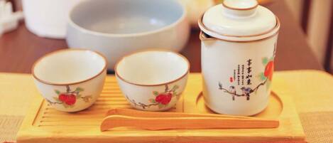 A traditional tea set with three cups and a teapot on a wooden tray.