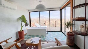 Ein modernes Zimmer mit einem großen Fenster, einer Badewanne und einem Essbereich.
