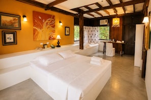A hotel room with a large bed, a small table with a chair, a sofa, and a window with curtains. - Hacienda Isabella Garden Resort (Indang)