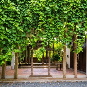 A covered walkway with a wooden pergola, steps leading to a building entrance, and a gravel path. - Hacienda Isabella Garden Resort (Indang)