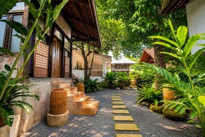Un bâtiment traditionnel doté d’une porte en bois, d’un escalier menant à une entrée abritée et d’un chemin recouvert de gravier.