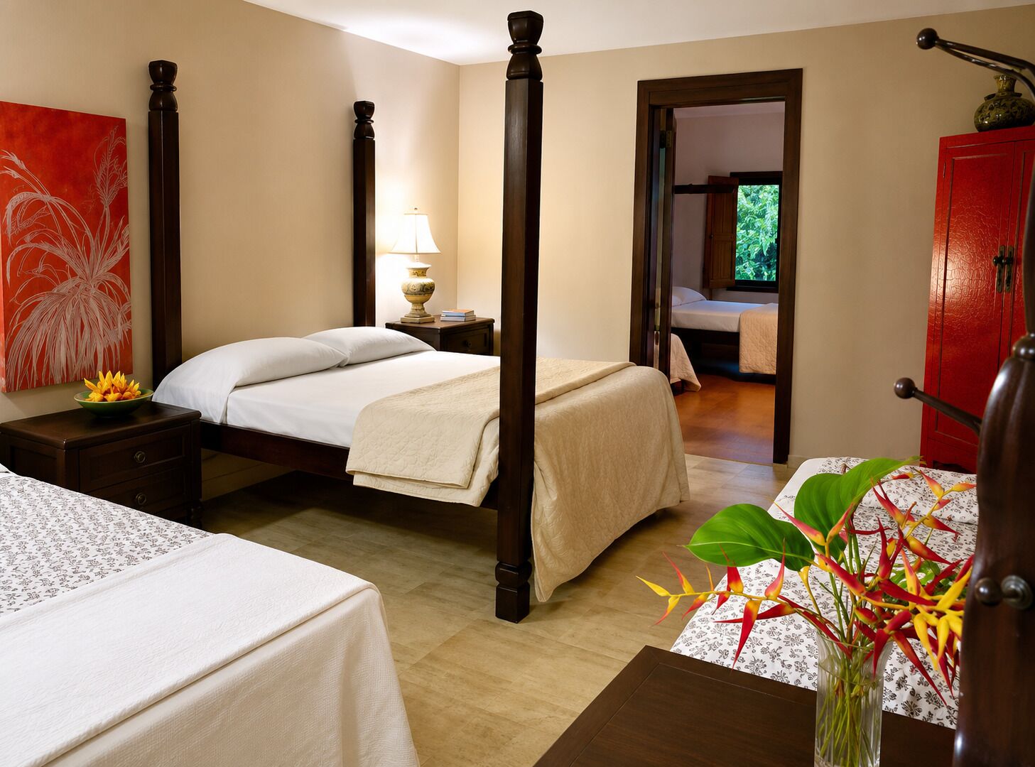 A hotel room with a four-poster bed, a bedside table with a lamp, a nightstand, and a view of a garden through an open door.