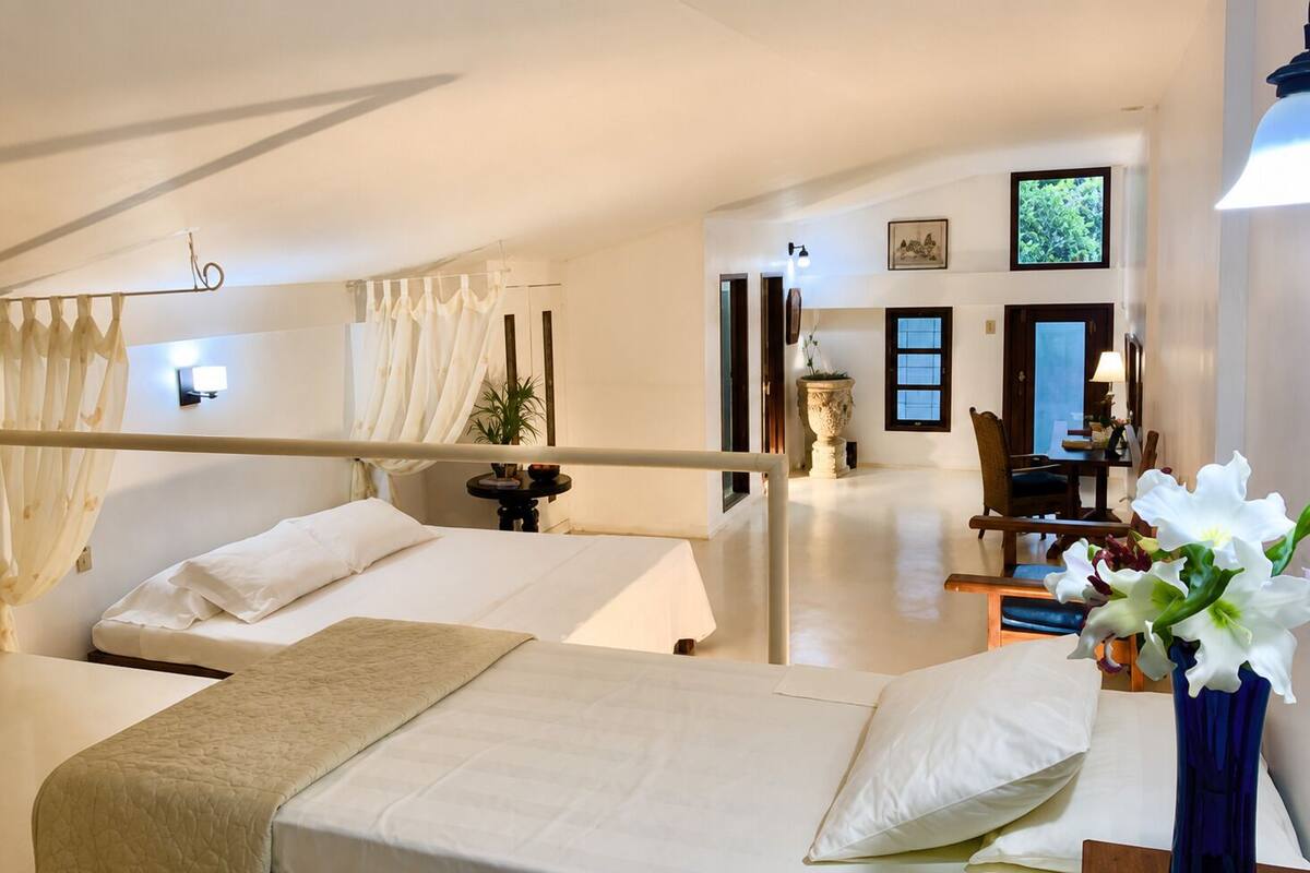 Een hotelkamer met twee bedden, een zithoek met een stoel en tafel, en uitzicht op het omliggende landschap.