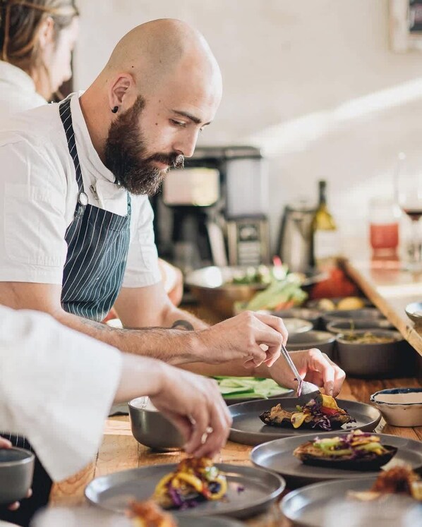 A chef preparing food in a kitchen with various dishes and cooking equipment.
