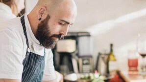 Um chef preparando comida em uma cozinha com diversos pratos e utensílios de cozinha.