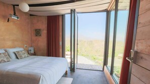 Quarto com uma cama grande, um projetor e vista para o exterior.