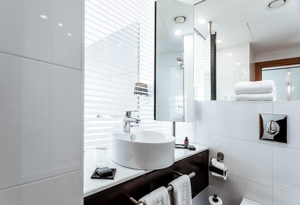 A modern bathroom with a large white sink, a mirror, and a toilet.