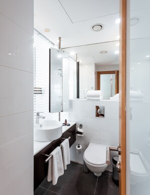 A modern bathroom with a large sink, toilet, and shower.