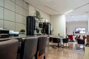 A modern hotel lobby with a bar area, seating arrangements, and a television screen.