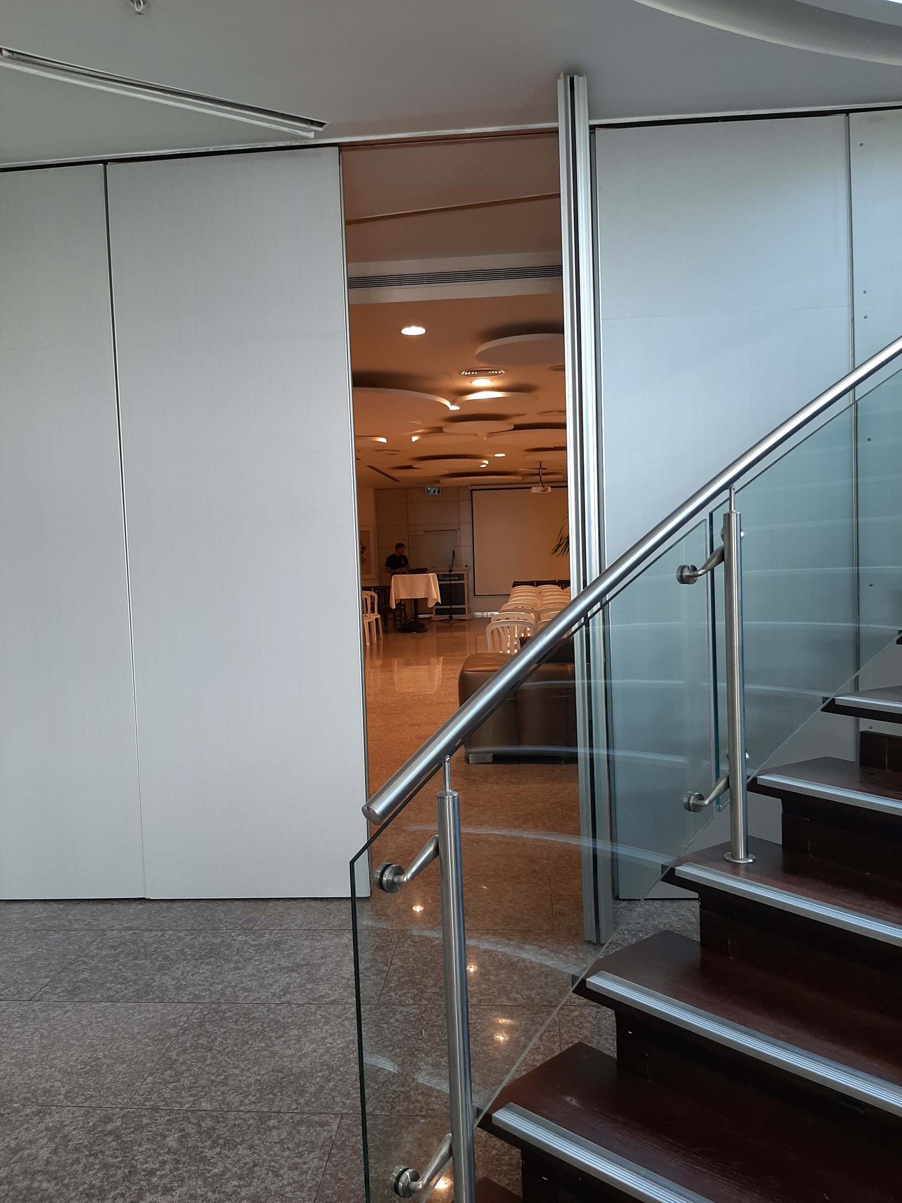Un intérieur moderne avec un escalier en verre, une salle de conférence et un espace d’accueil.