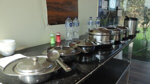 A kitchen counter with stainless steel cookware, water bottles, and a coffee maker. - Royal Chuka Farm Stay (Puranpur)