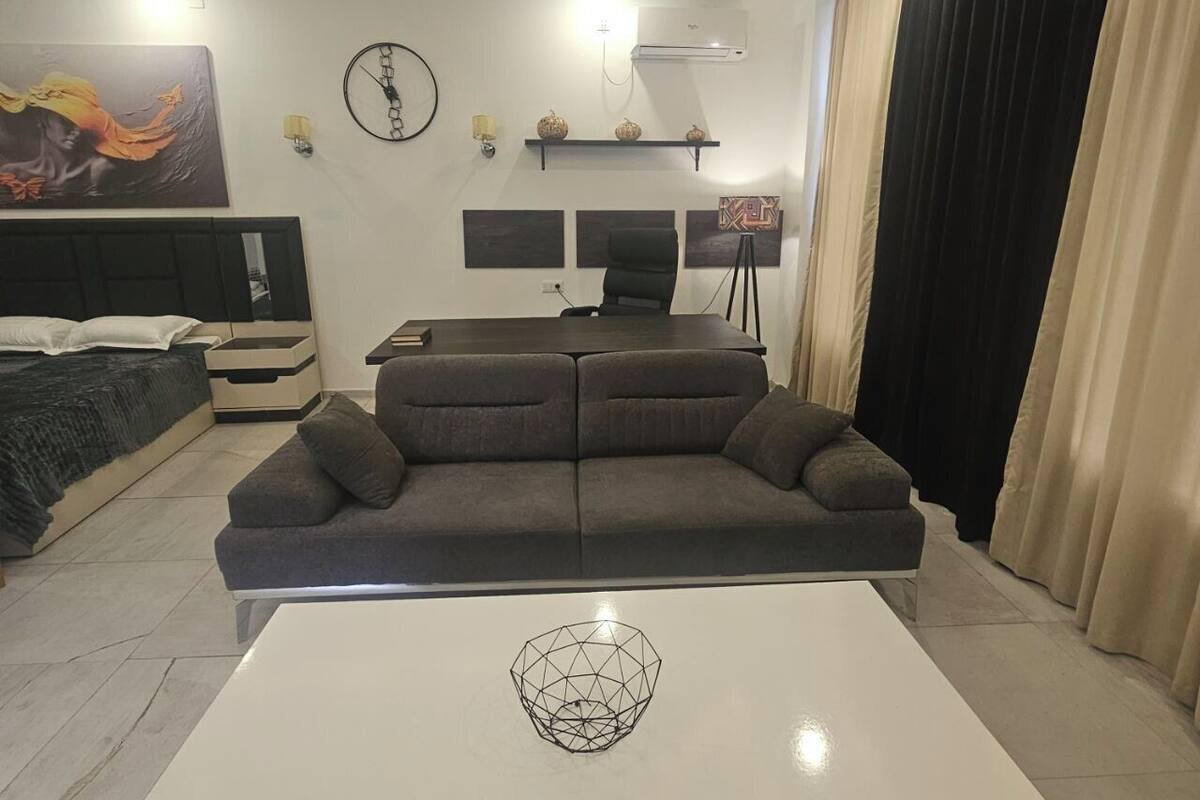 Een moderne woonkamer met een bank, een salontafel, een bed, een bureau en een televisie.
