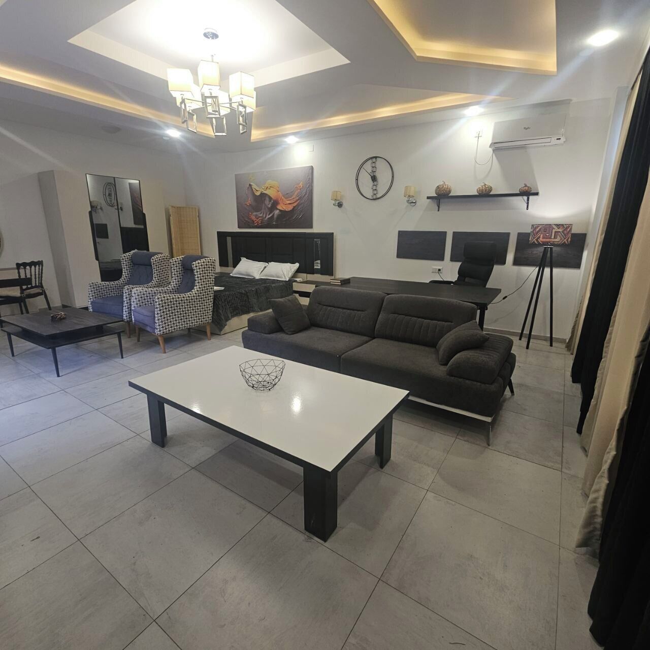 Een moderne woonkamer met een bank, een salontafel, en een eethoek met stoelen en een tafel.