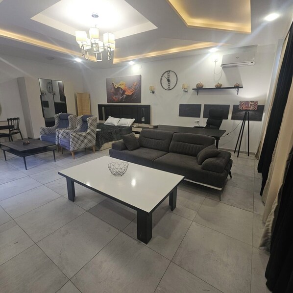 A modern living room with a sofa, a coffee table, and a dining area with chairs and a table. - batumi green park hotel (Batumi)