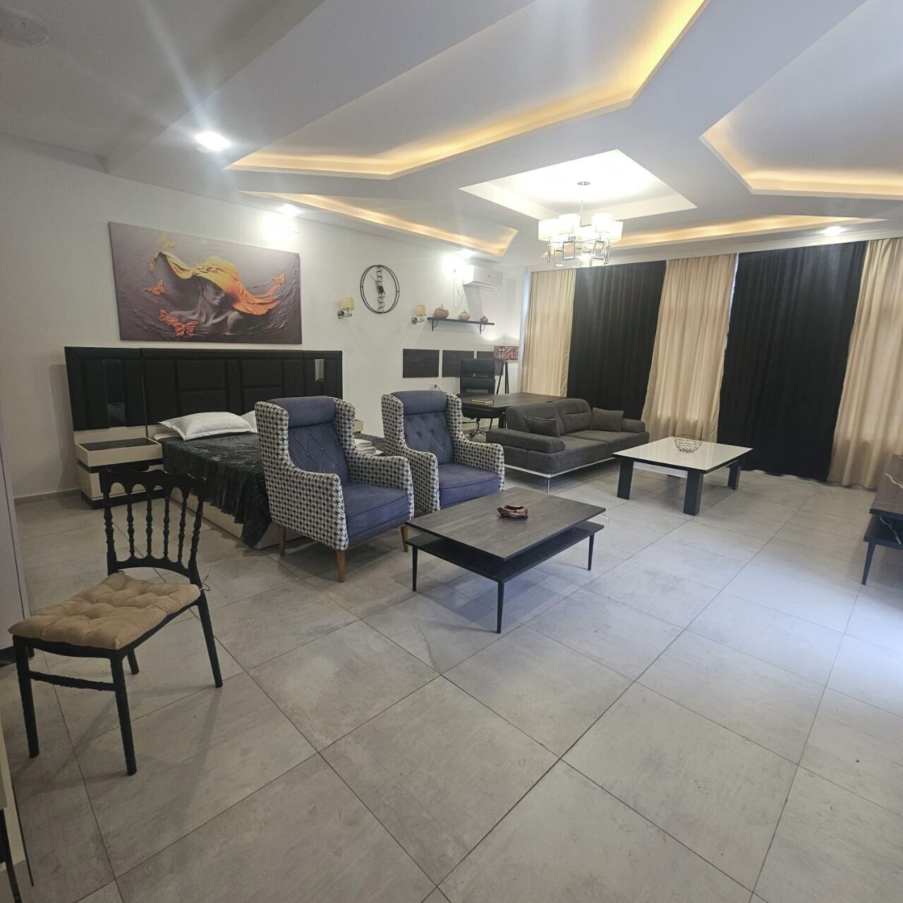A modern living room with a sofa, armchairs, a coffee table, and a TV.