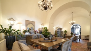 A spacious dining area with a wooden table, upholstered chairs, and a chandelier. - Villa Kalisa in Sorrento (Sorrento)
