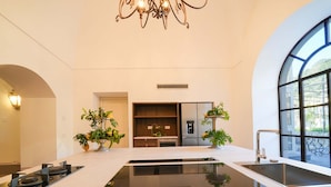 A modern kitchen with a central island, built-in appliances, and large windows offering natural light. - Villa Kalisa in Sorrento (Sorrento)