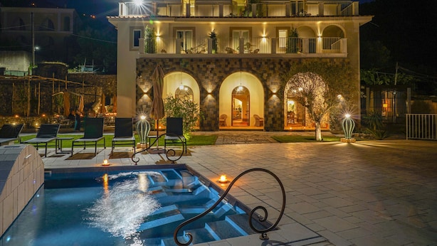 A hotel with a swimming pool, outdoor seating, and a well-lit entrance. - Villa Kalisa in Sorrento (Sorrento)