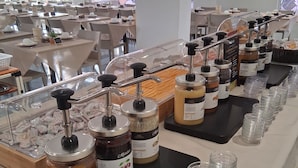 A buffet setup with various food items and condiment dispensers. - Hotel Aron Rimini (Rimini)