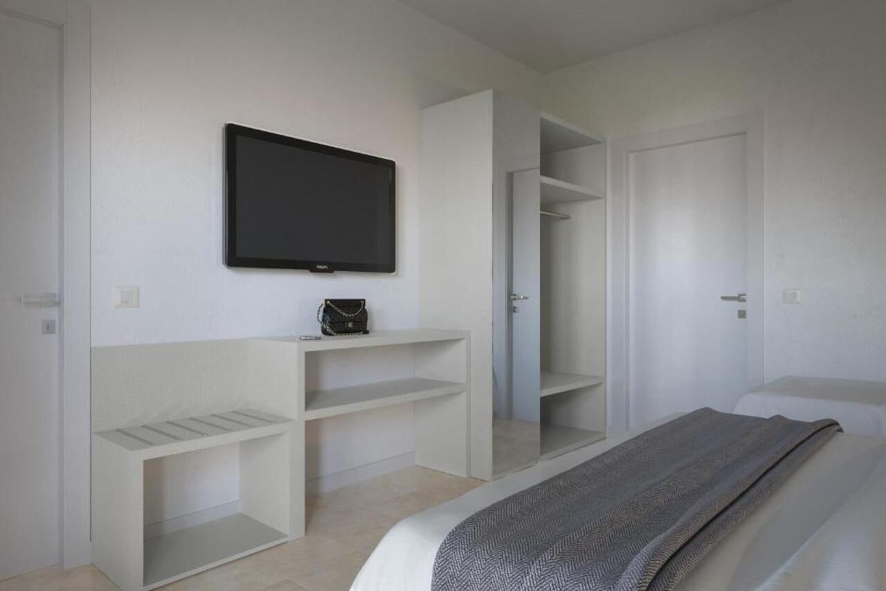 A bedroom with a bed, a TV mounted on the wall, and built-in shelving.