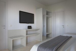 A bedroom with a bed, a TV mounted on the wall, and built-in shelving.