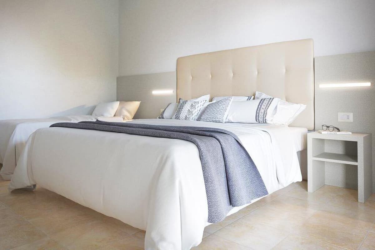 A modern hotel room with a large bed, a bedside table, and a nightstand.