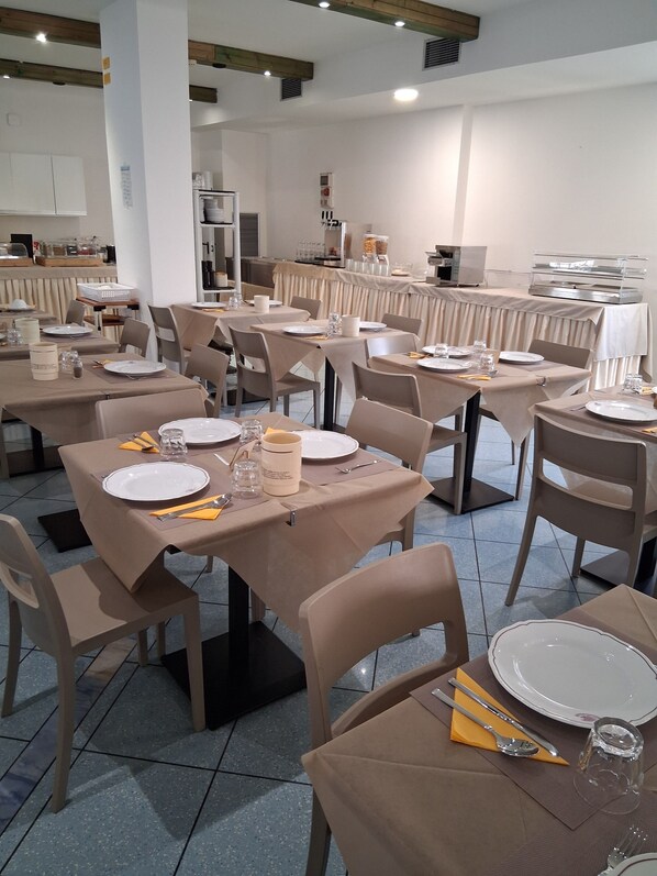 A restaurant with multiple tables set for dining, equipped with plates, cutlery, and glasses. - Hotel Aron Rimini (Rimini)