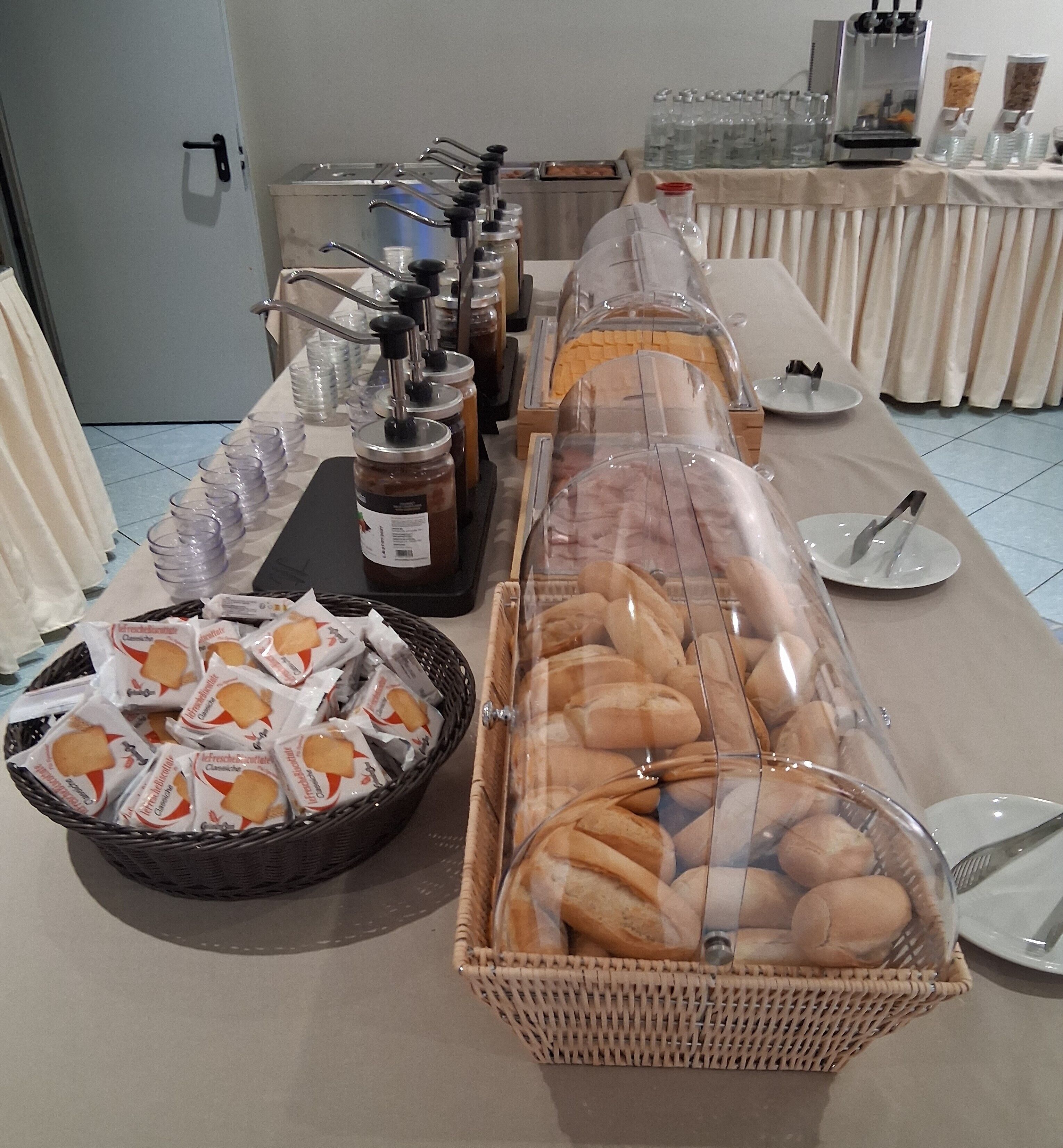 A buffet setup with bread, condiments, and beverages.