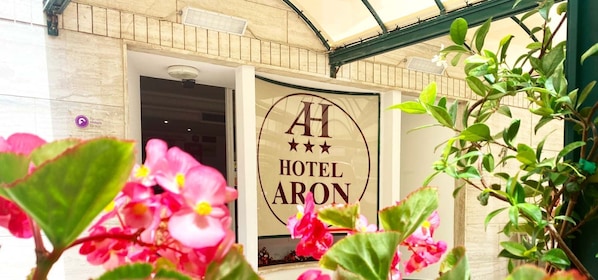 A hotel entrance with a sign reading "HOTEL ARON" and a logo with three stars. - Hotel Aron Rimini (Rimini)