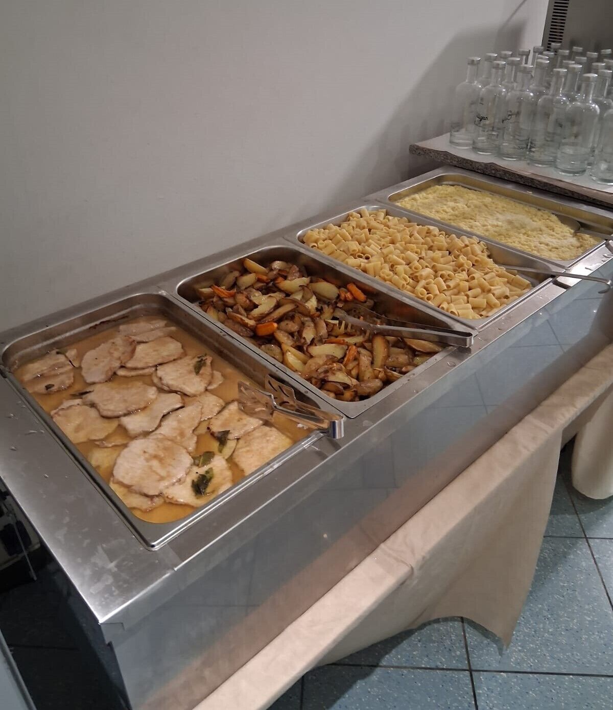 A buffet with various food options including pasta, vegetables, and meat dishes.