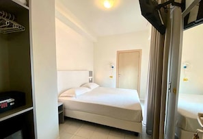 A hotel room with a bed, a wardrobe, a mirror, and a door. - Hotel Aron Rimini (Rimini)