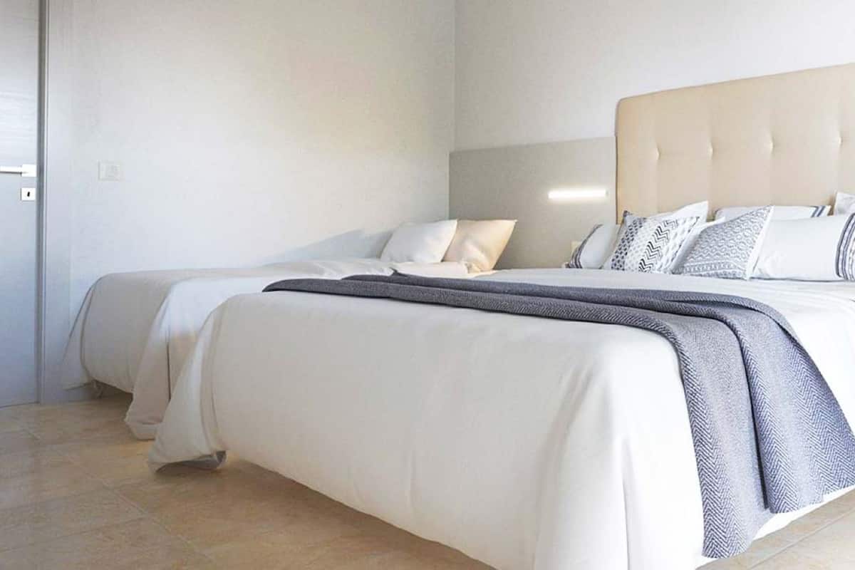 A modern bedroom with a large bed, a bedside table, and a built-in shelf.