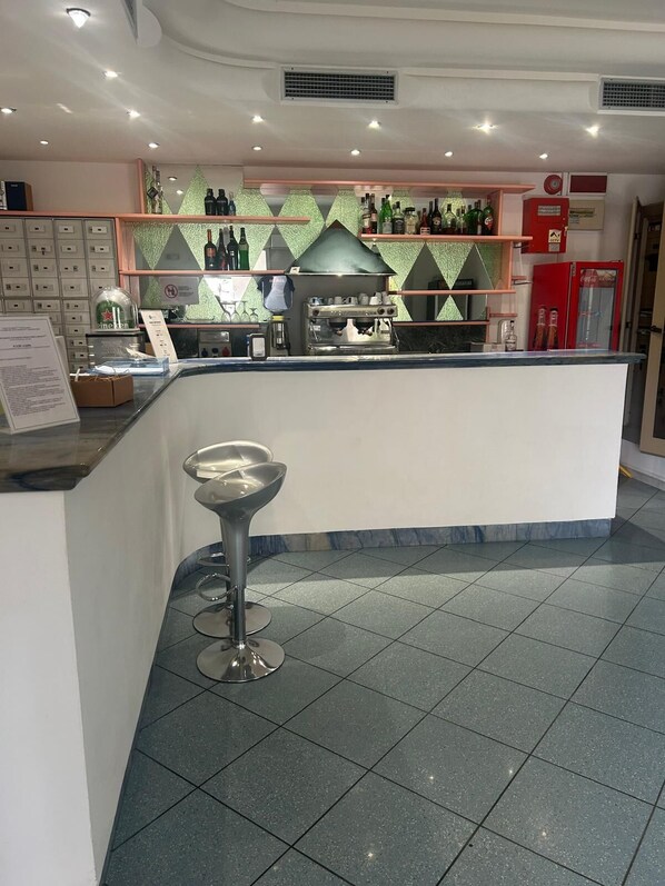 A bar area with a counter, stools, and shelves with bottles.