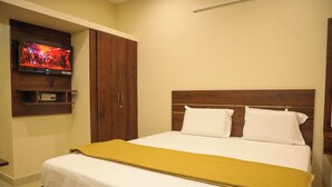 Hotelkamer met een bed, een aan de muur bevestigde televisie, een kledingkast en een plank met een afstandsbediening.