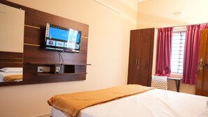 Een hotelkamer met een bed, een aan de muur bevestigde televisie, een kledingkast en een raam met gordijnen.