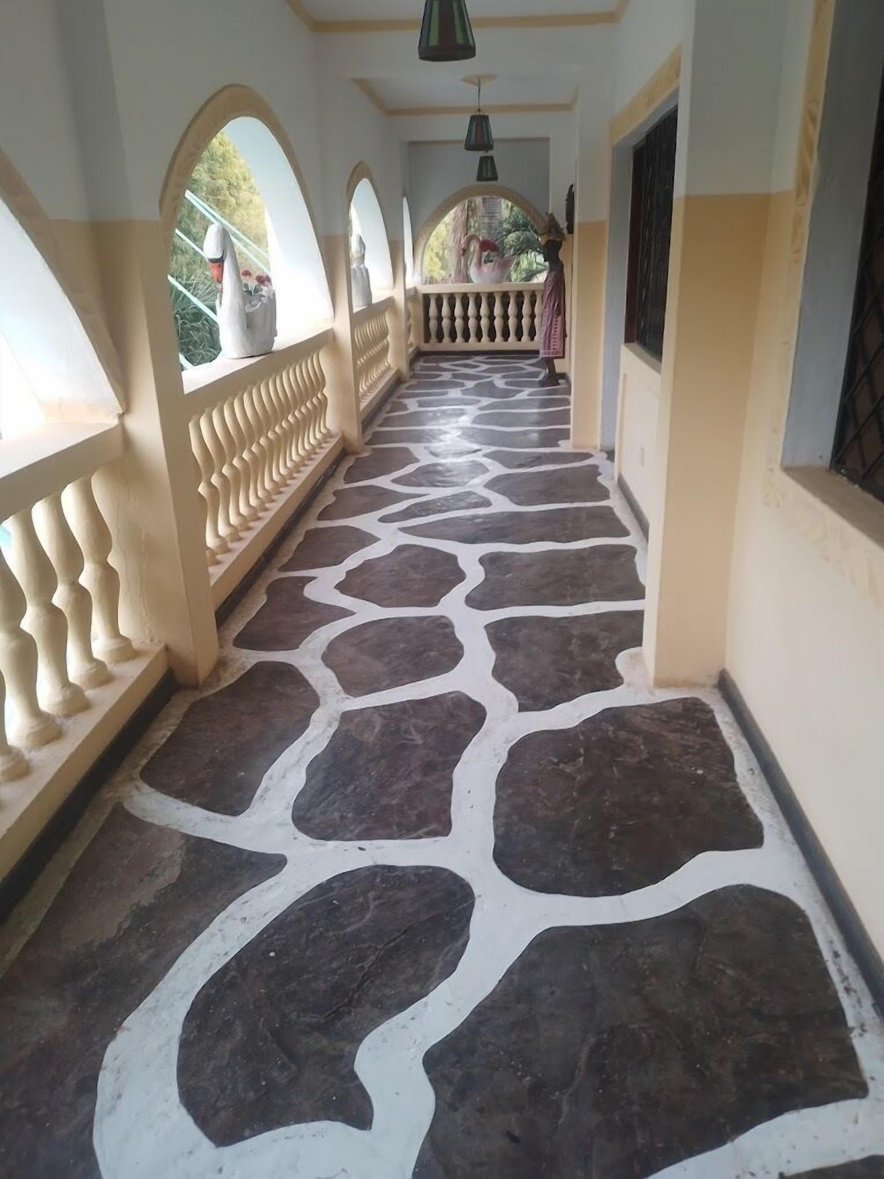A corridor with a patterned stone floor, white walls, and decorative railings.